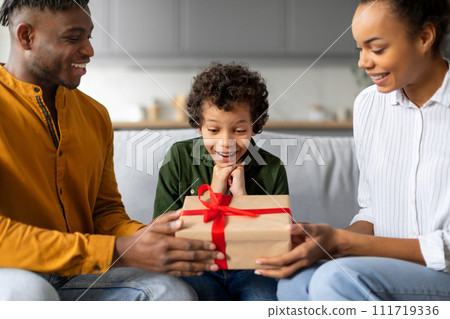 Surprised child boy receiving gift from parents, happy family moment Surprised child boy receiving gift from parents, happy family moment 111719336