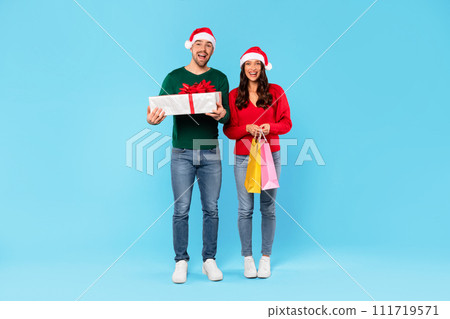 Happy Couple Holding Shopper Bags And Wrapped Present, Blue Background 111719571