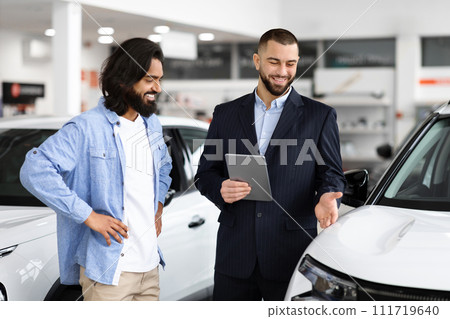 Indian guy standing by nice white car, talking to dealer 111719640