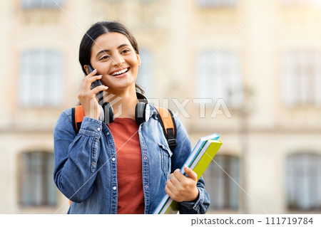 Joyful pretty young woman student talking on phone outdoor Joyful pretty young woman student talking on phone outdoor 111719784