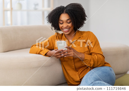 Cheerful millennial curly african american woman chatting on phone Cheerful millennial curly african american woman chatting on phone 111719846