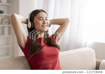 Beautiful Smiling Asian Woman In Wireless Headphones Listening Music At Home, Beautiful Smiling Asian Woman In Wireless Headphones Listening Music At Home, 111719848