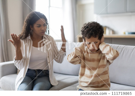 Family argument. Offended black boy covering ears, not to listen mother's scolding 111719865