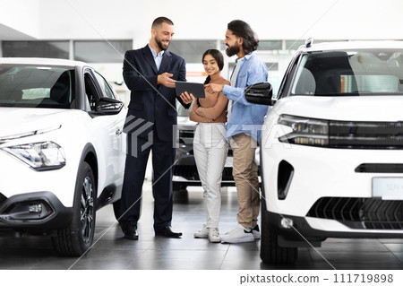 Attractive car salesman with tablet shares details about new car 111719898