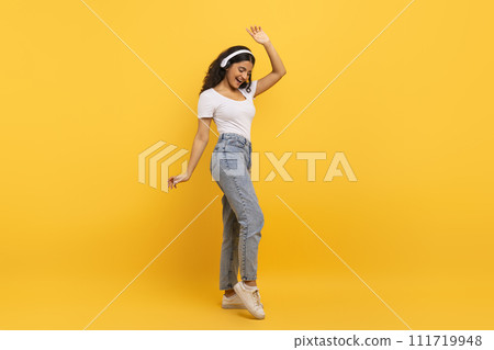 Overjoyed young indian woman using headphones and dancing Overjoyed young indian woman using headphones and dancing 111719948