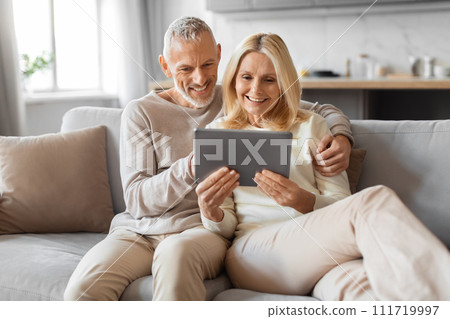 Positive retired couple using digital tablet at home Positive retired couple using digital tablet at home 111719997