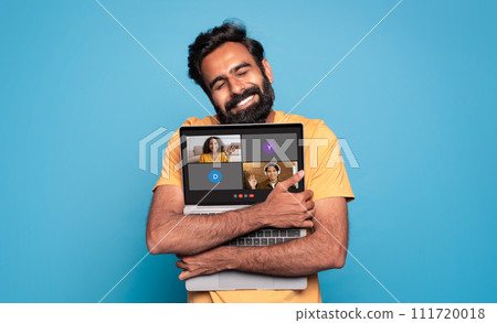 A contented man with a beard lovingly embraces his laptop, displaying a virtual meeting A contented man with a beard lovingly embraces his laptop, displaying a virtual meeting 111720018