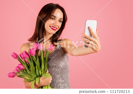 Smiling young woman takes a selfie with her smartphone, capturing the moment Smiling young woman takes a selfie with her smartphone, capturing the moment 111720213