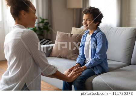Black mother conversing with her son, sitting comfortably at home 111720378