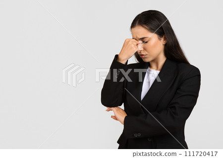 Worried businesswoman with hand on bridge of nose, eyes closed Worried businesswoman with hand on bridge of nose, eyes closed 111720417