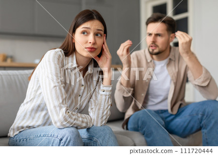 Frustrated man gesturing in argument with woman at home 111720444