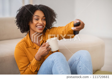 Smiling young african american woman enjoy cup of coffee in hands Smiling young african american woman enjoy cup of coffee in hands 111720681