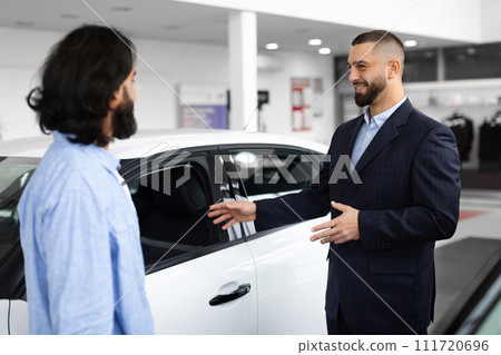 Young car salesman making deal with customer at the dealership 111720696