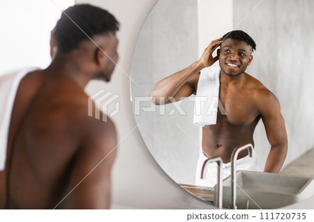 Handsome African American Man Smiles At Reflection In Bathroom Mirror 111720735