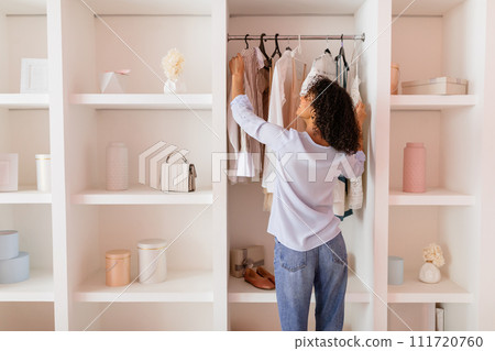 Woman arranging clothes in a chic, open closet 111720760