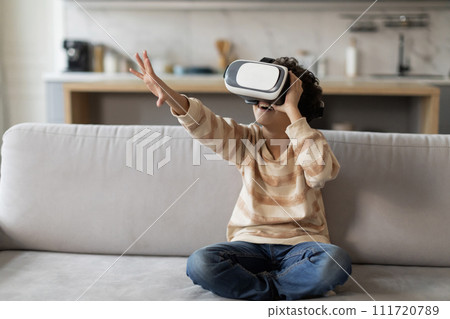 Excited black little boy wearing virtual reality headset having fun at home 111720789