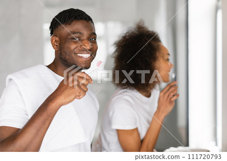 Happy black couple engages in oral care brushing teeth indoors Happy black couple engages in oral care brushing teeth indoors 111720793