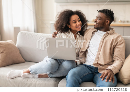 African American spouses enjoying watching video online on laptop indoor 111720818