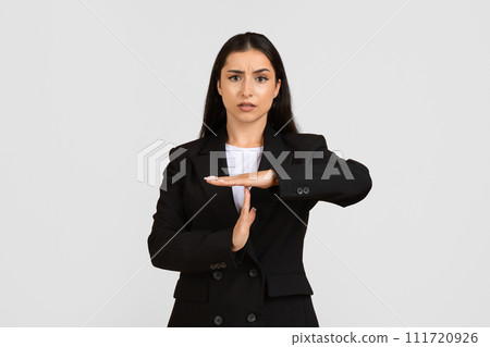 Serious young european businesswoman making time out gesture 111720926
