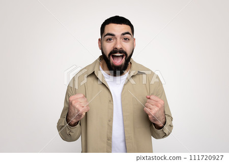 Happy shocked handsome young latin man winner with beard in casual with open mouth 111720927