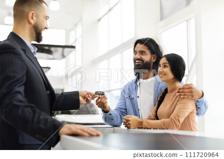 Smiling eastern young couple buying car at auto salon 111720964