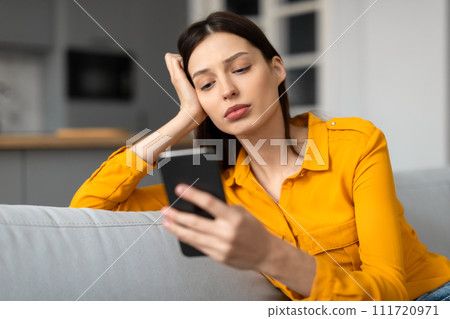 Stressed young woman with phone looking troubled 111720971