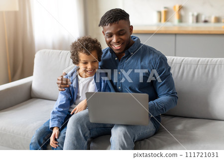 Black father and son bonding over laptop at home 111721031