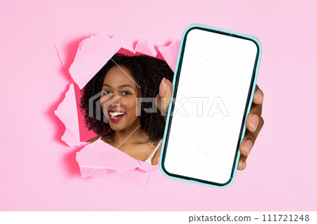 black lady holding cellphone showing through hole in pink background 111721248
