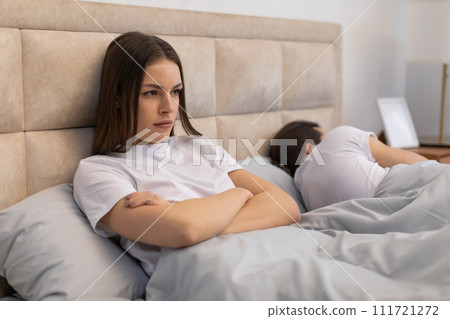 Woman awake and upset in bed with man sleeping Woman awake and upset in bed with man sleeping 111721272