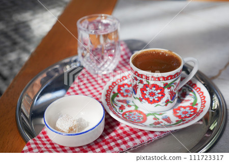 a cup of turkish coffee served with water and turkish delight on table  111723317