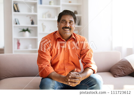 Positive middle aged eastern man sitting on couch at home 111723612