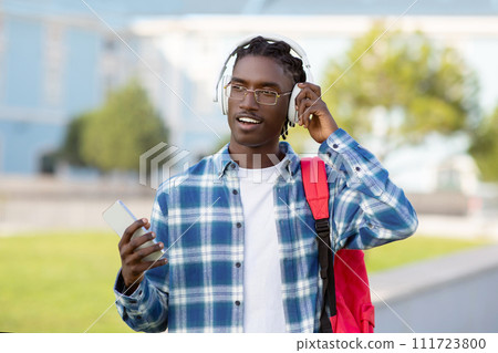 black student with backpack uses smartphone to browse playlist outdoor black student with backpack uses smartphone to browse playlist outdoor 111723800