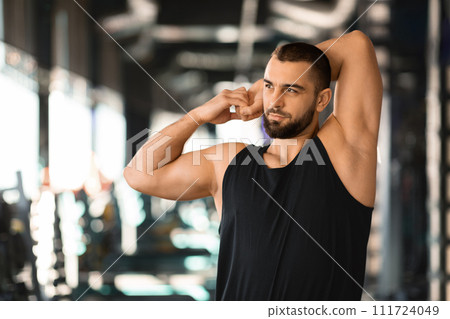 Portrait Of Athletic Young Man Stretching Arm Muscles At Gym Portrait Of Athletic Young Man Stretching Arm Muscles At Gym 111724049