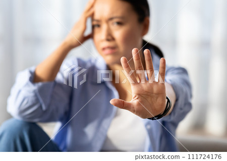 Asian woman showing stop gesture, home interior Asian woman showing stop gesture, home interior 111724176