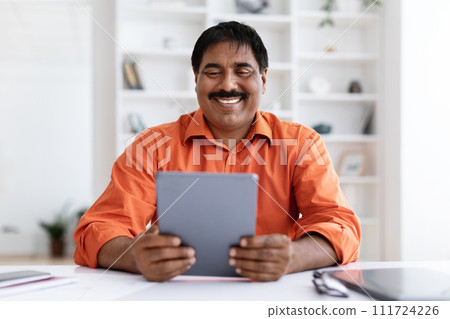 Smiling mature indian man entrepreneur holding using digital tablet pc 111724226