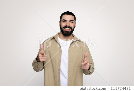 Glad confident handsome young latin man with a beard in casual point fingers at camera Glad confident handsome young latin man with a beard in casual point fingers at camera 111724481