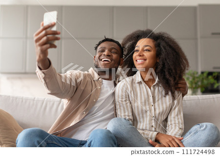 Loving happy black young spouses video calling via cellphone indoor Loving happy black young spouses video calling via cellphone indoor 111724498