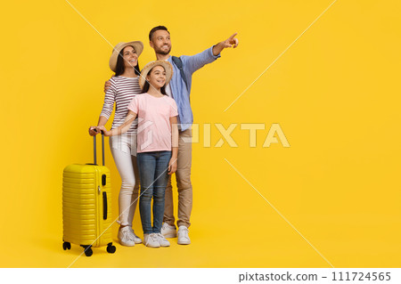Family Travel Concept. Happy parents with daughter carrying suitcase and pointing aside 111724565