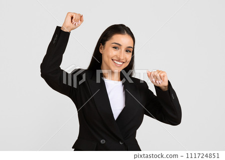 Joyful european businesswoman celebrating success with raised arms 111724851