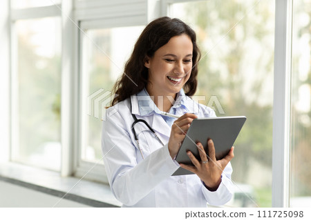 Smiling young woman doctor using digital tablet Smiling young woman doctor using digital tablet 111725098