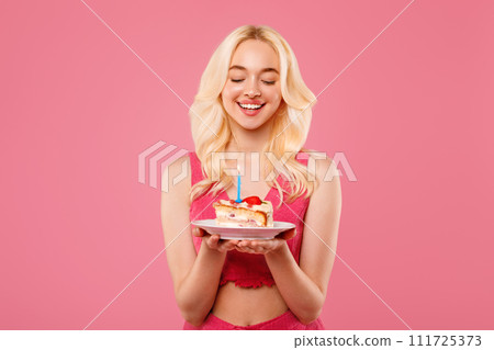 Blissful young woman with birthday cake, eyes closed in wish 111725373