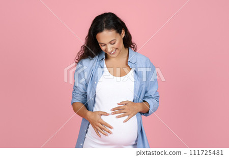Young brunette woman expecting baby, pink background Young brunette woman expecting baby, pink background 111725481