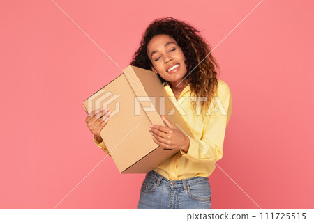 Joyful young black woman hugging parcel, smiling on pink backdrop Joyful young black woman hugging parcel, smiling on pink backdrop 111725515