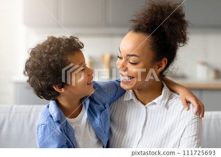 Joyful black mother and son share tender moment and embracing at home 111725693