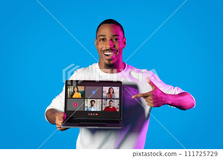 A cheerful man in a white shirt points with both hands to a laptop screen 111725729