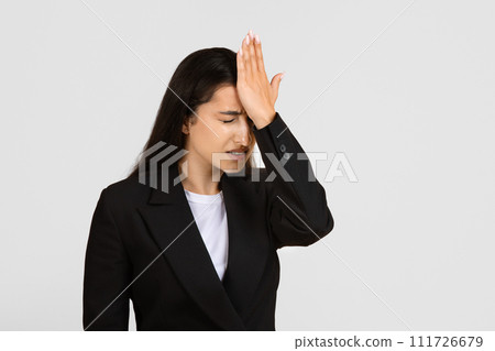 Regretful businesswoman with hand on forehead in forgetful moment 111726679