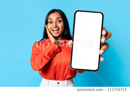 Excited Indian woman shows large phone with blank screen, studio 111726715