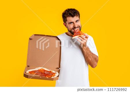 Caucasian man savoring slice of pizza from delivery box, studio Caucasian man savoring slice of pizza from delivery box, studio 111726992