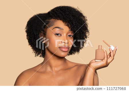 Serene young black woman presenting liquid foundation bottle 111727068