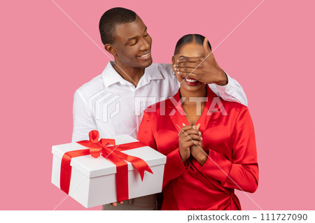 Black man surprises delighted woman with gift box 111727090